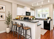 Thumbnail 2 of 8 - A kitchen with a black countertop and white cabinets.