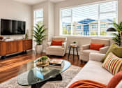 Thumbnail 4 of 8 - A living room with a glass coffee table and a flat screen TV on the wall.