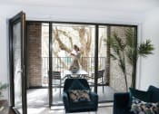 Thumbnail 3 of 7 - a woman standing on a balcony in a living room with sliding glass doors