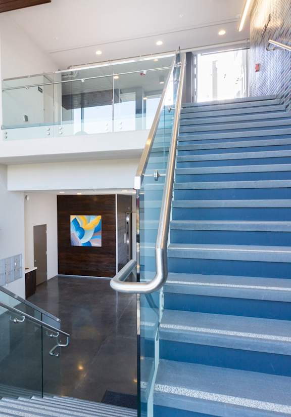 A staircase with a glass railing and a blue tiled wall.