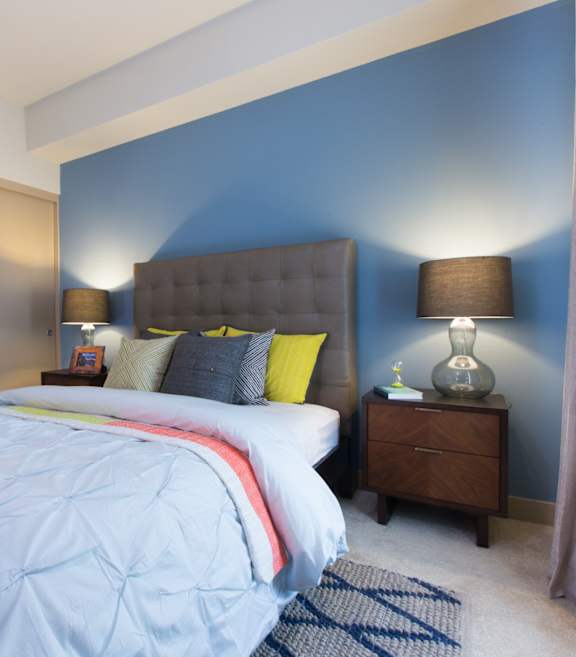 A bedroom with a large bed and a nightstand with a lamp.