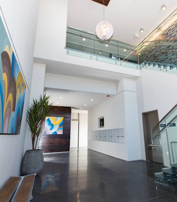 A hallway with a glass staircase and a painting on the wall.
