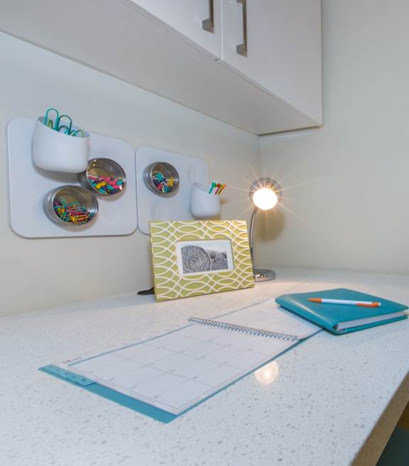 A white desk with a notebook and a planner on it.