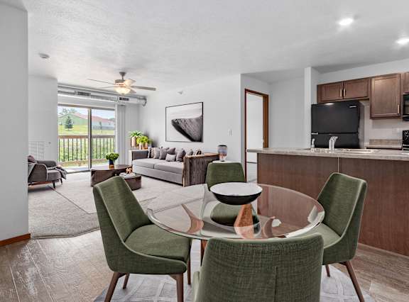 A modern dining room with a glass table and green chairs.