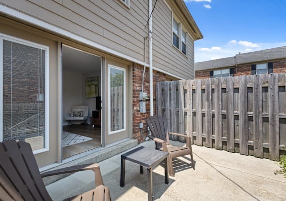 A patio with a table and chairs is in front of a house.
