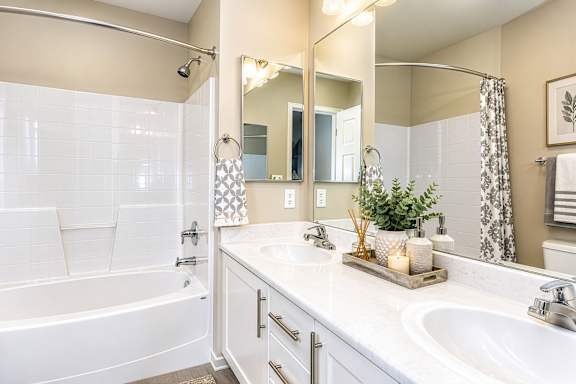 A white bathroom with a large mirror and a bathtub.