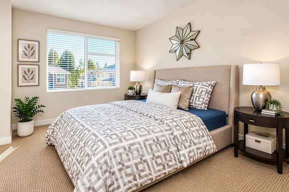 A bedroom with a large bed and a window with blinds.