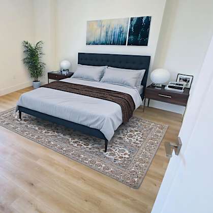 A bedroom with a bed, chair, and plant.