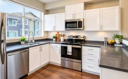A kitchen with white cabinets and black countertops.