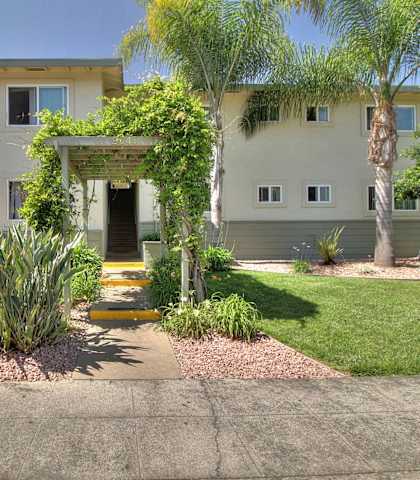 the front of a house with a walkway and plants