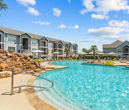 A large swimming pool in front of a resort-style building.