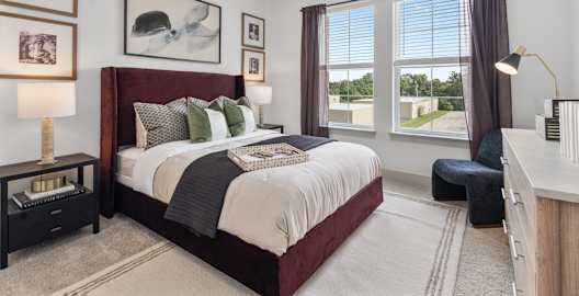 A bedroom with a large bed and a window overlooking a green landscape.