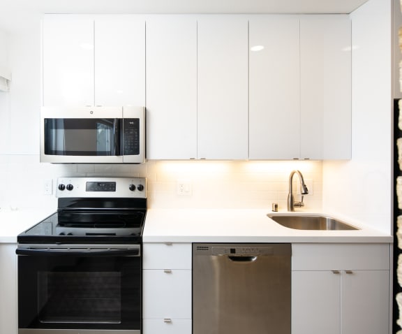 a kitchen with white cabinets and black appliances
