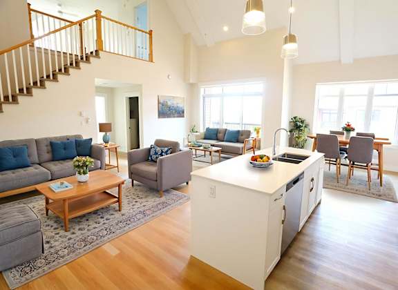 A spacious open floor plan of a modern home with a kitchen, dining area, and living room.
