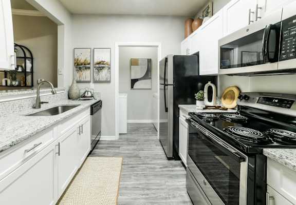 A modern kitchen with black and white appliances and a grey floor.