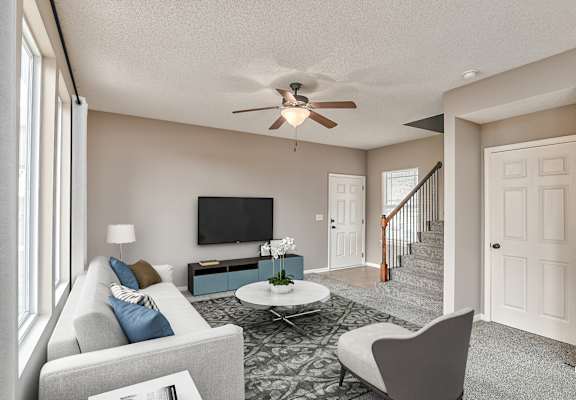 A living room with a grey couch, a coffee table, and a staircase.