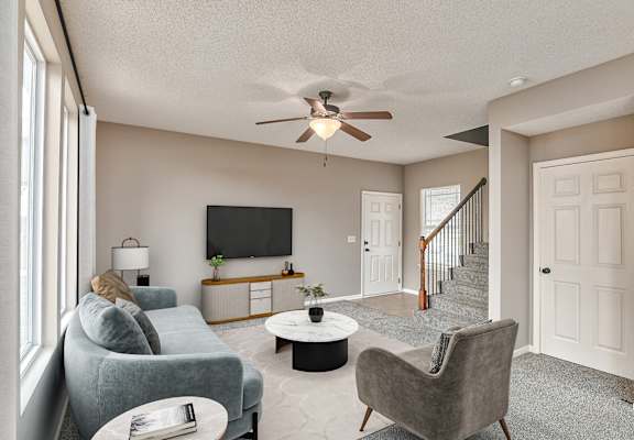 a living room with couches and chairs and a ceiling fan