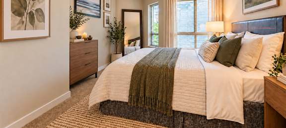A bedroom with a large bed and a painting on the wall.