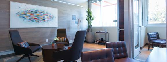 A modern living room with a large abstract artwork on the wall and a variety of seating options.