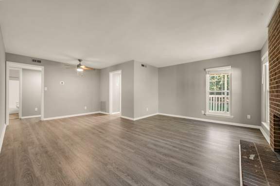 A room with wooden flooring and a window with a view of a balcony.