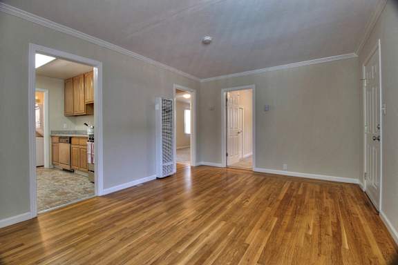 A room with wooden floors and a window with blinds.
