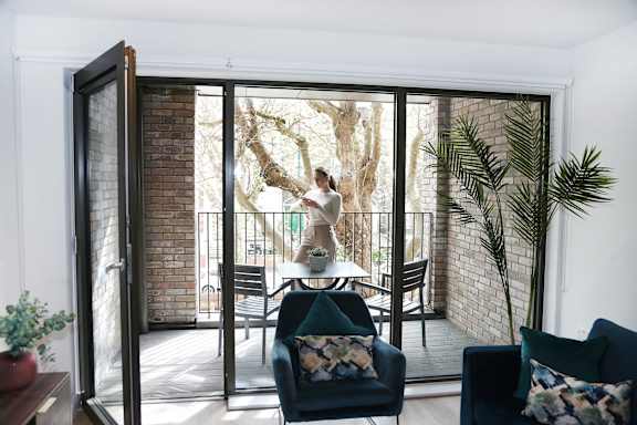 a woman standing on a balcony in a living room with sliding glass doors