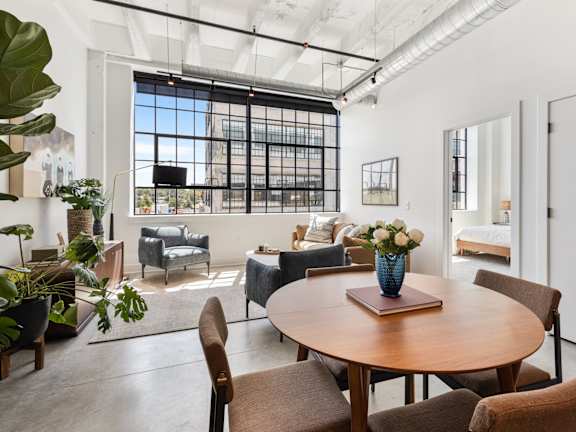 A modern living room with a kitchen area in the background.
