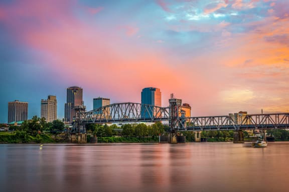 the city at sunset with the bridge over the river at Esplanade District Apartments, Little Rock