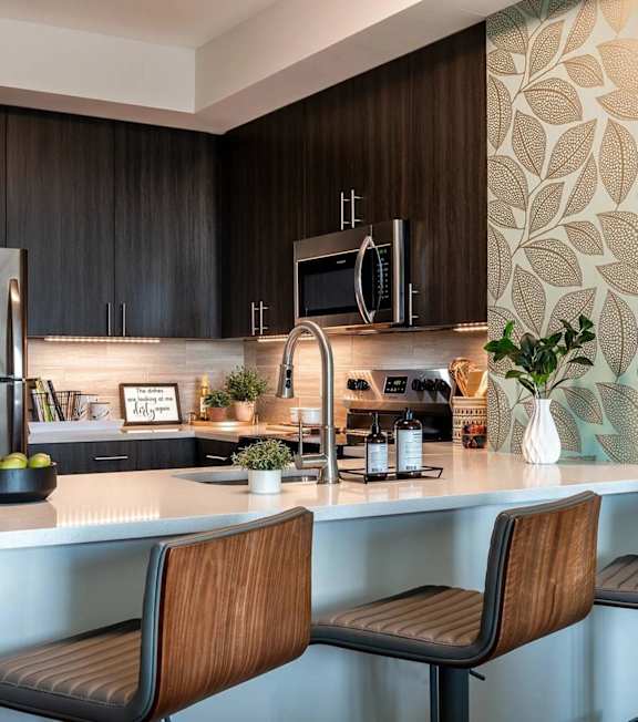 A modern kitchen with a refrigerator, microwave, and a bench.