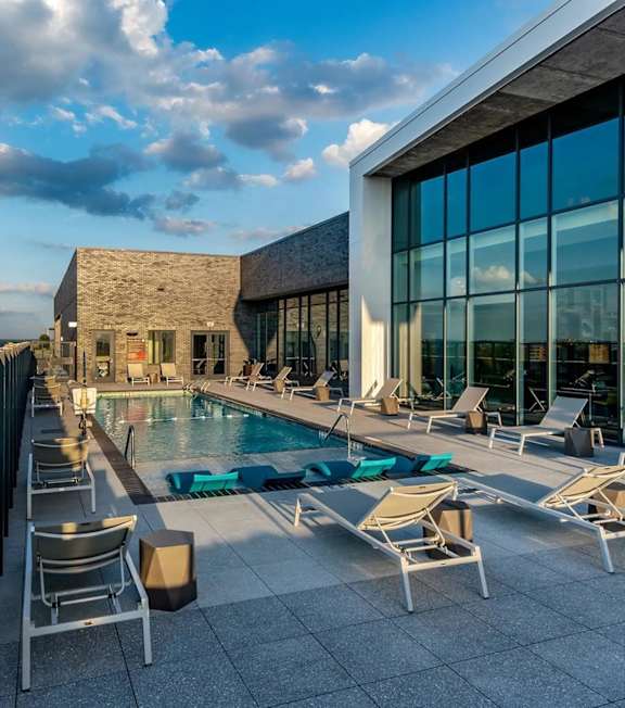A modern building with a pool and lounge chairs.