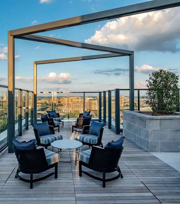 A wooden deck with chairs and tables overlooking a cityscape.