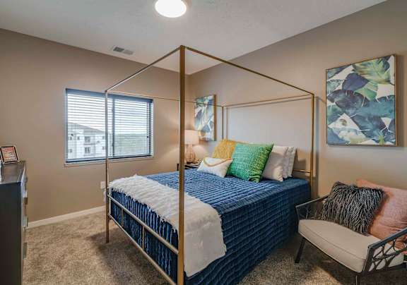 a bedroom with a bed and a chair and a window