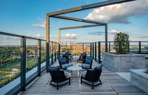 A wooden deck with chairs and tables overlooking a cityscape.