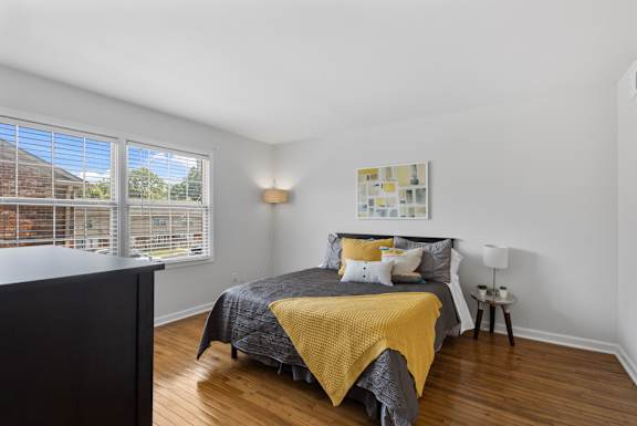Primary bedroom at Monon Living with large windows and wood flooring, located in a walkable Broad Ripple community near Monon Trail bike access.