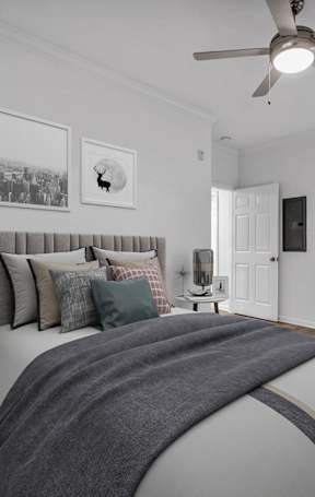 A bedroom with a bed, nightstand, and a painting on the wall.
