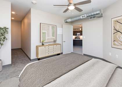 A bedroom with a bed, dresser, and ceiling fan.