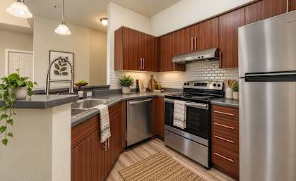 A modern kitchen with wooden cabinets and stainless steel appliances.
