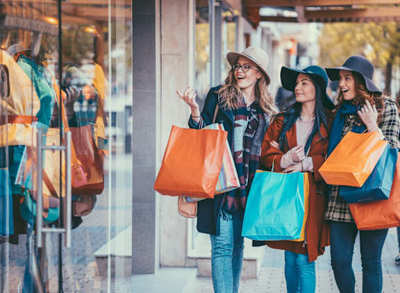 Three women are walking together, each carrying a shopping bag.