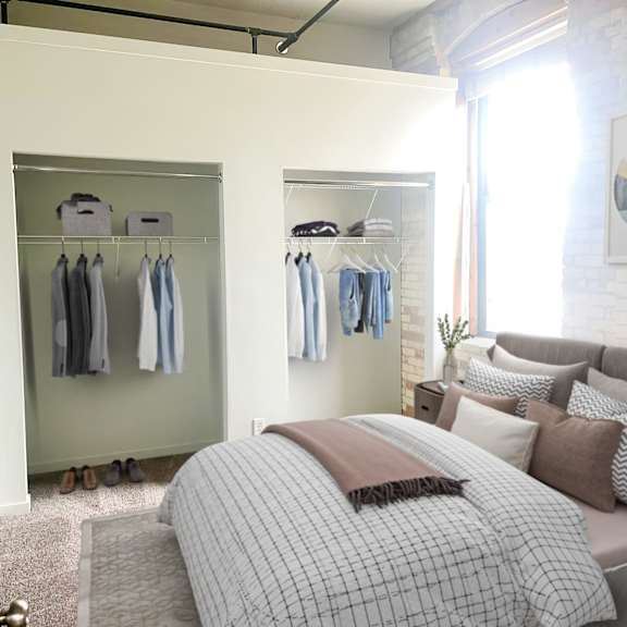 A bedroom with a bed, pillows, a couch, and a clothing rack.