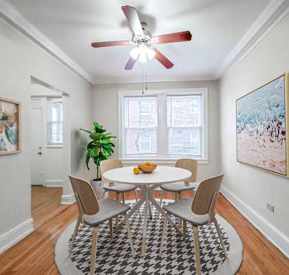 A dining room with a table and chairs and a ceiling fan.