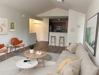 a living area with a couch coffee table and chairs and a kitchen in the background