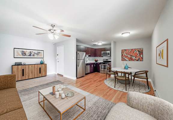 a living room with a couch a table and a chair and a kitchen with a stove and