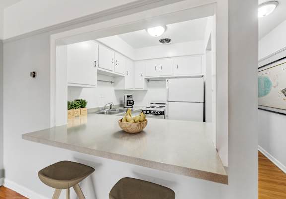 a kitchen with white cabinets and a white counter top with a bowl of fruit on it