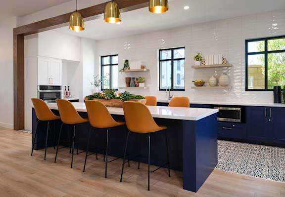 a kitchen with a large white island and four brown chairs