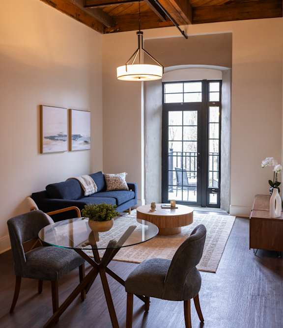 A black wicker chair with a white cushion is on a balcony overlooking a river. at The Dean at Creekview Apartments, Newark, Delaware