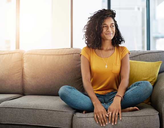 Woman Sitting on Comfortable Couch at Thornberry Woods Apartment Homes in Naperville