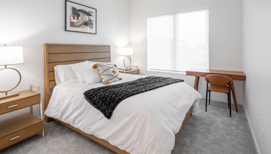 a bedroom with a bed and a desk and a window
