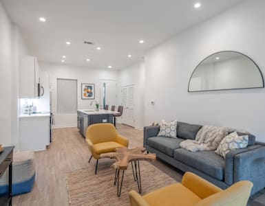 a living room with a couch and chairs and a kitchen