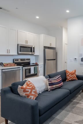 a living room with a couch and a kitchen with a sink and a microwave