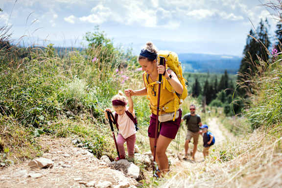 A family of hikers, including a child, are walking on a trail in a natural setting at Apex, Colorado Springs, Colorado